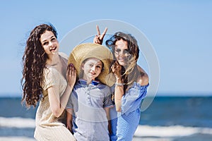 Mother daughter and a boy in a straw hat messing around.