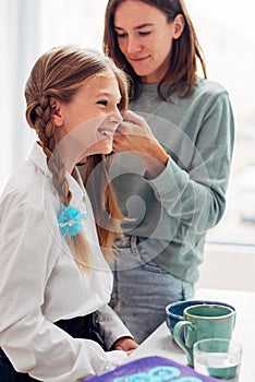 Mother and daughter at breakfast before school in the kitchen braiding braids