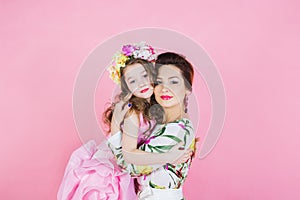 Mother and daughter in bright dresses on a pink background