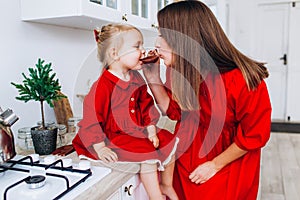 Mother and daughter in a bright kitchen. Homeliness. Joyful baby and his mom.