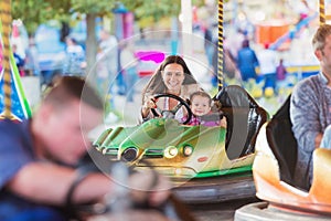 Mother and daughter in bumper car at fun fair