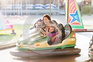 Mother and daughter in bumper car at fun fair