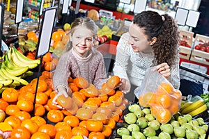 Mother and daughter buying ripe fruits together