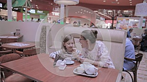 Mother with daughter in cafe. Eating ice-cream, talking, having fun.