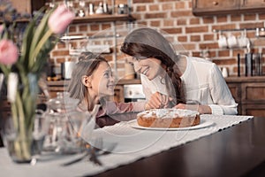 Mother and daughter with cake on table, mother`s day holiday concept
