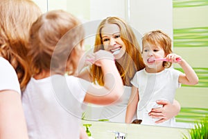 Mother and daughter child girl brushing her teeth toothbrushes f