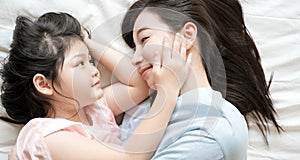 Mother and daughter child girl spending time together in the bedroom Look at each other and smiling .Happy Asian family.