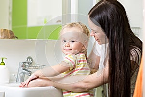 Mother and daughter child girl washing hands with soap in bathroom