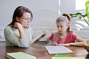 Mother and daughter child study together at home, sitting at table