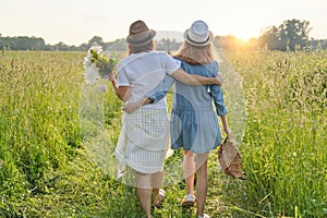 Mother and daughter child walking along the meadow, view from the back