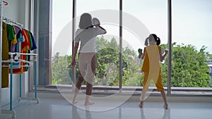 Mother and daughter are cleaning, wiping the glass and dancing happily.