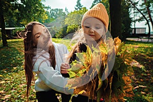 Mother with daughter collect a bouquet of autumn leaves at the park