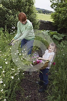 Mother And Daughter Collecting Flowers In Garden