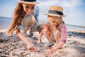 Mother and daughter collecting seashells