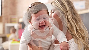 Mother and daughter consueling baby crying at kindergarten