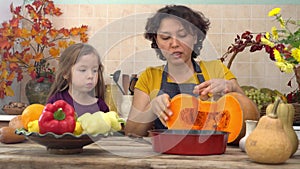 Mother and daughter cook pumpkin meals at home. Cooking together for a festive Thanksgiving dinner. A farmer's family