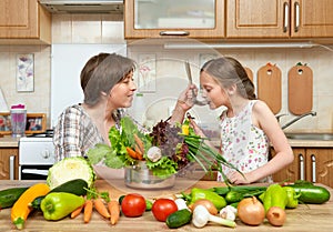 Mother and daughter cook and taste soup from vegetables. Home kitchen interior. Parent and child, woman and girl. Healthy food con photo