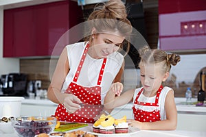 Mother and daughter cooking cupcakes on the festive table