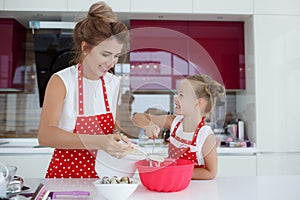 Mother and daughter cooking cupcakes on the festive table