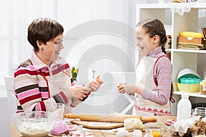 Mother and daughter cooking at home, making the dough for buns