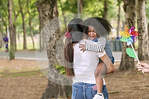 Mother daughter crying in the park. Little black girl crying while her mother caring on the arms standing under big tree