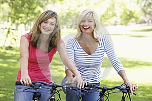 Mother And Daughter Cycling Through A Park