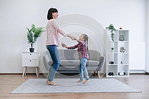 Mother and daughter dancing barefoot on carpet in lounge