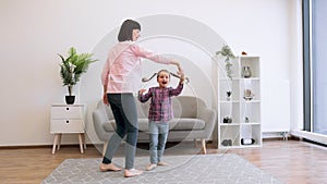 Mother and daughter dancing barefoot on carpet in lounge