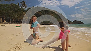Mother with daughter dancing on shallow water sea. Woman with her girl child enjoying her vacation on tropical island