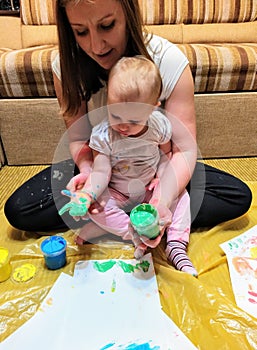 Mother and daughter do handprints with green paint