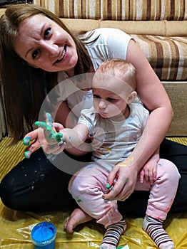 Mother and daughter do handprints with green paint