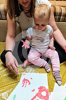 Mother and daughter do handprints with red paint