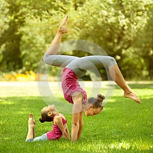 Mother and daughter doing exercise outdoors.