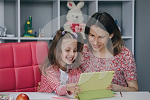 Mother and daughter doing homework online. Distance learning online education. Schoolgirl with digital tablet laptop