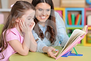 Mother and daughter doing homework together in room photo