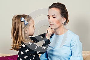 Mother and daughter are doing makeup. Lovely mom and child having fun together. Happy Mother`s Day