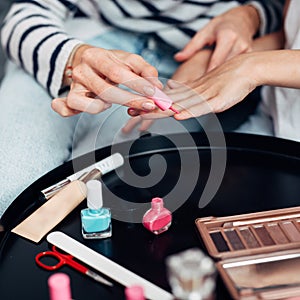 Mother and daughter doing manicure at home, painting nails with nail polish