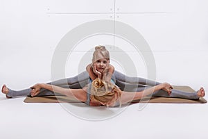 Mother daughter doing yoga exercise,fitness family sports, sports paired woman sitting on the floor stretching his legs apart in