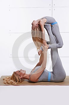 Mother daughter doing yoga exercise fitness gym wearing the same comfortable tracksuits family sports paired woman lies on back li