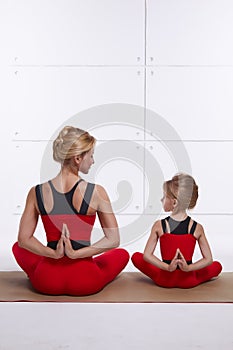 Mother daughter doing yoga exercise, fitness, gym wearing the same comfortable tracksuits, family sports, sports paired