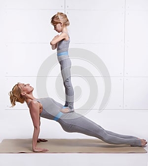 Mother and daughter doing yoga exercise, fitness, gym wearing the same comfortable tracksuits family sports, sports paired woman