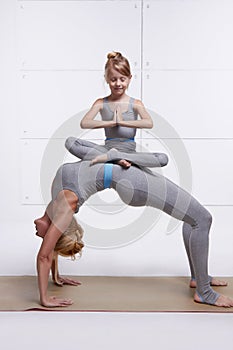 Mother and daughter doing yoga exercise, fitness gym wearing same woman standing in posture of bridge hands and feet resting on th