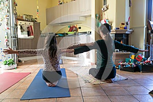 Mother and daughter doing yoga exercises on rug at home