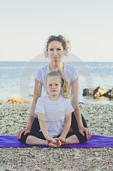 Mother and daughter doing yoga outdoors