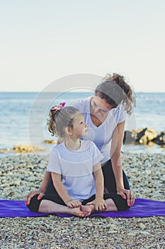 Mother and daughter doing yoga outdoors