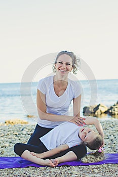 Mother and daughter doing yoga outdoors