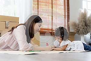 Mother and daughter drawing and coloring with colored pencils lying down on the floor. Happy family moment in the house.Art