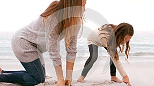 Mother and daughter drawing in the sand