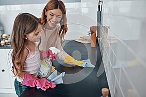 Mother and daughter dusting using washing up gloves