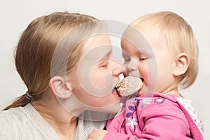 Mother with daughter eat and bitting gingerbread